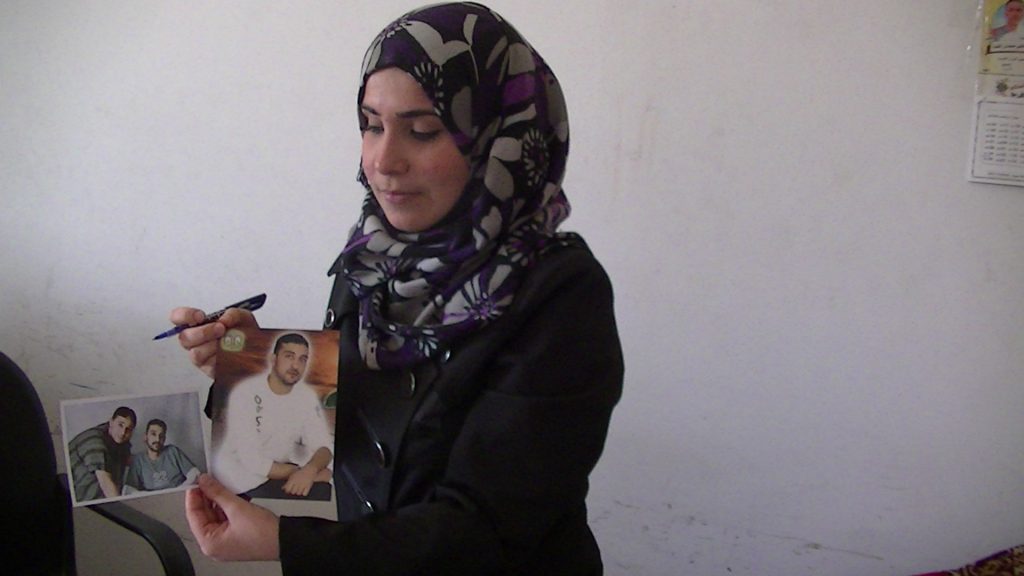 Mukarram Abu Alouf from the government Ministry of Detainees holds up two pictures of Rabee Ali, one before he was arrested and one on the day he was released. Rabee died soon after his release - photo taken by Corporate Watch, Gaza City, November 2013